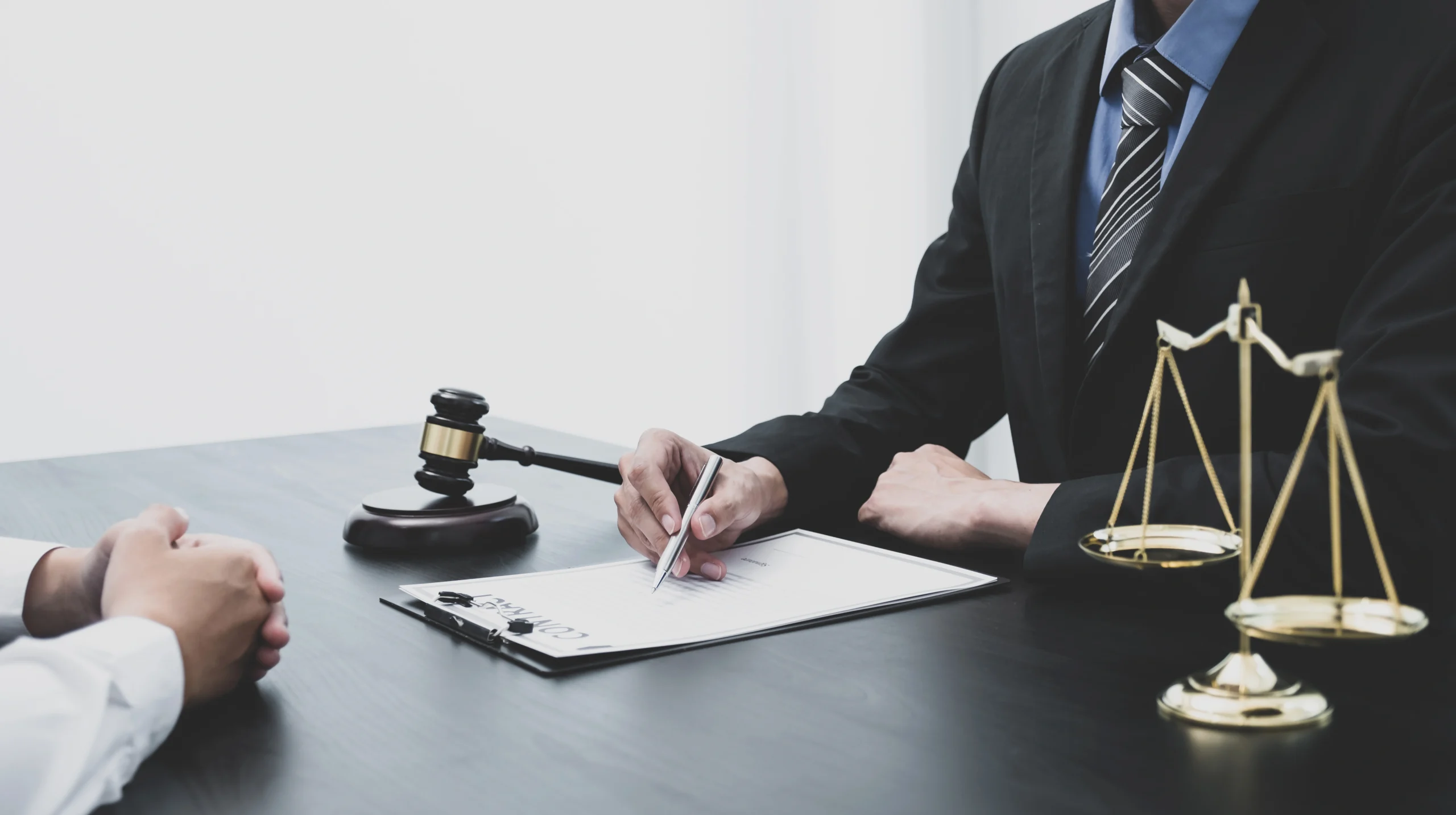 A lawyer goes over a contract on a clip board at a desk with someone