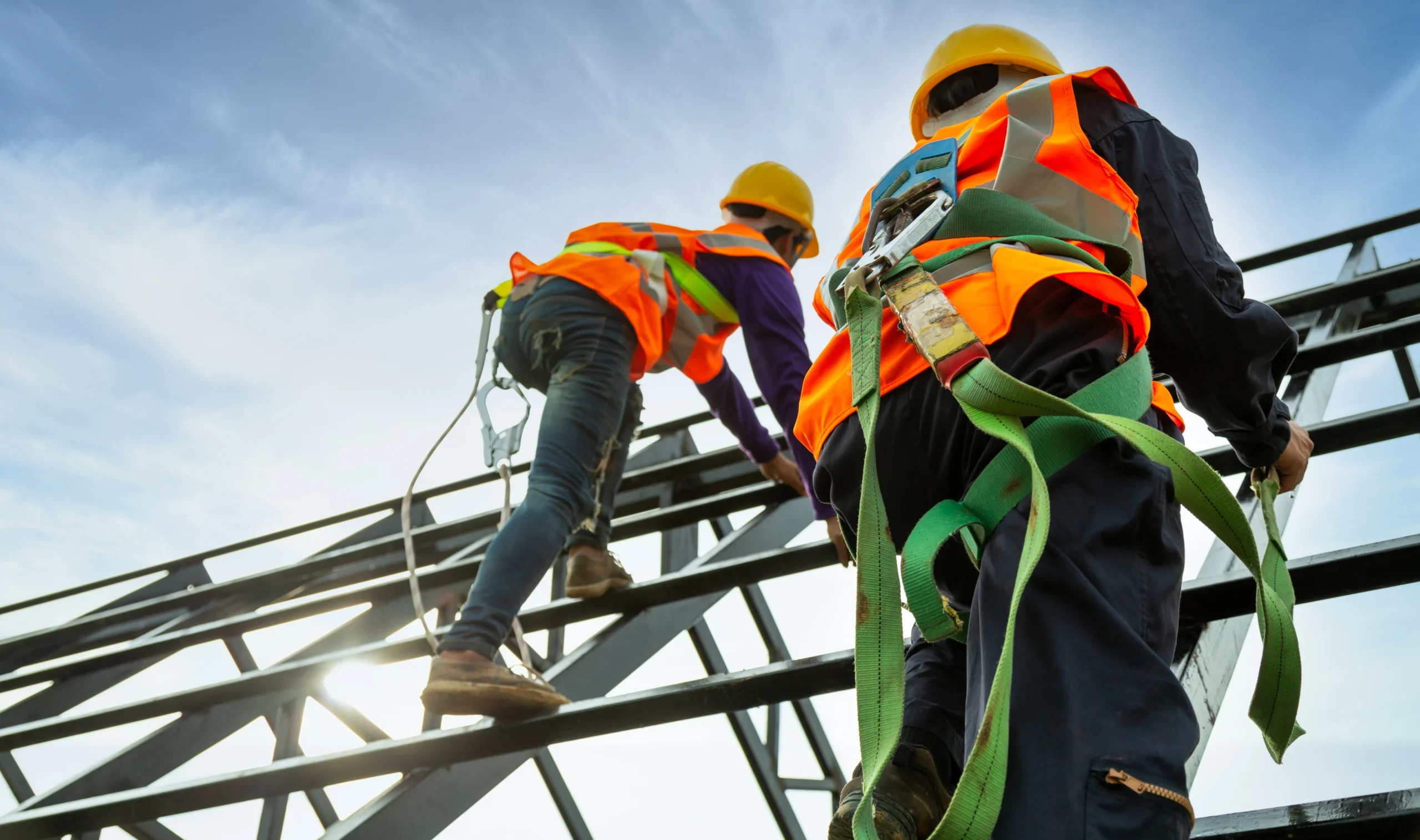 Two construction workers climb up scaffolding