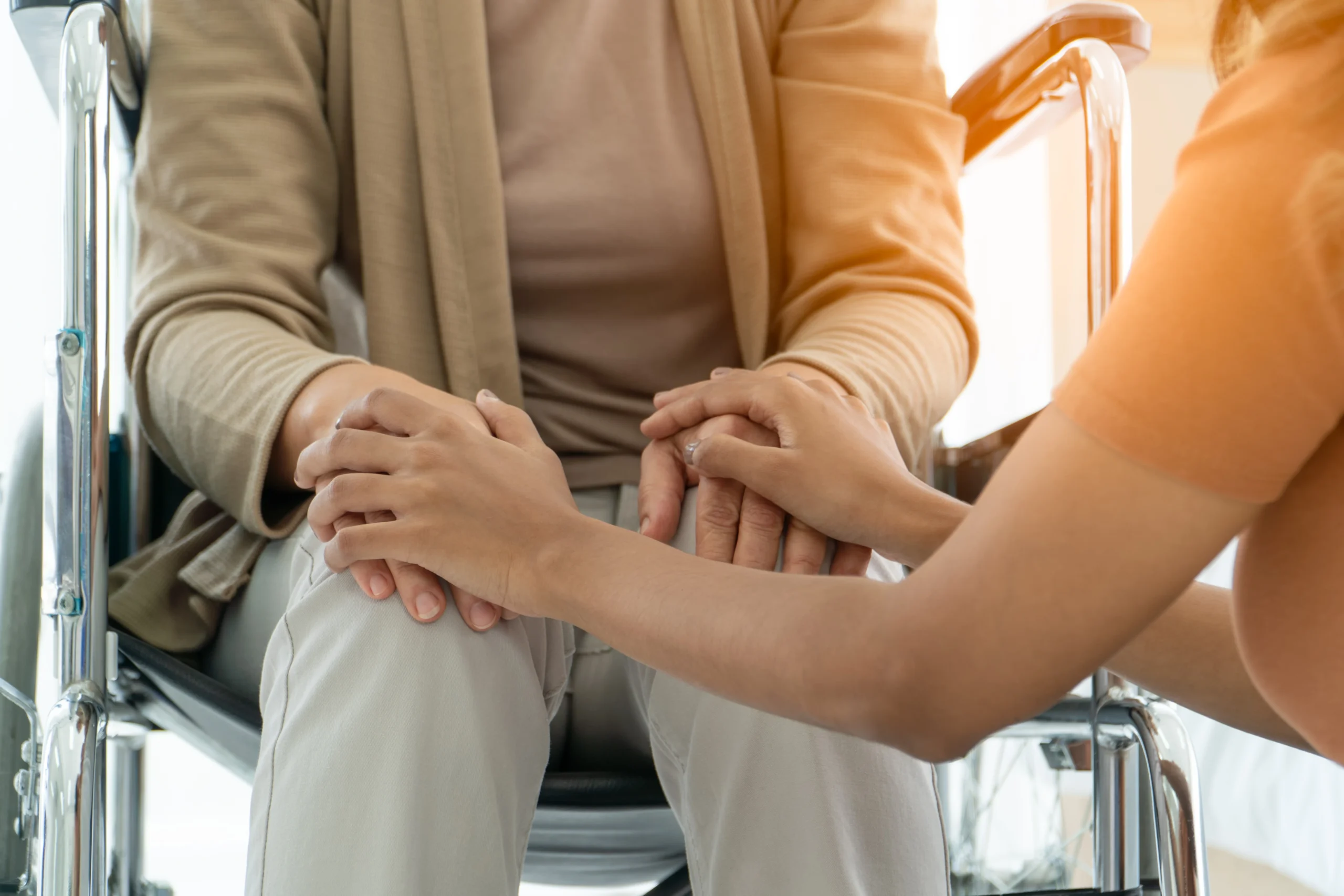 A young person puts their hands on an elderly person's hand