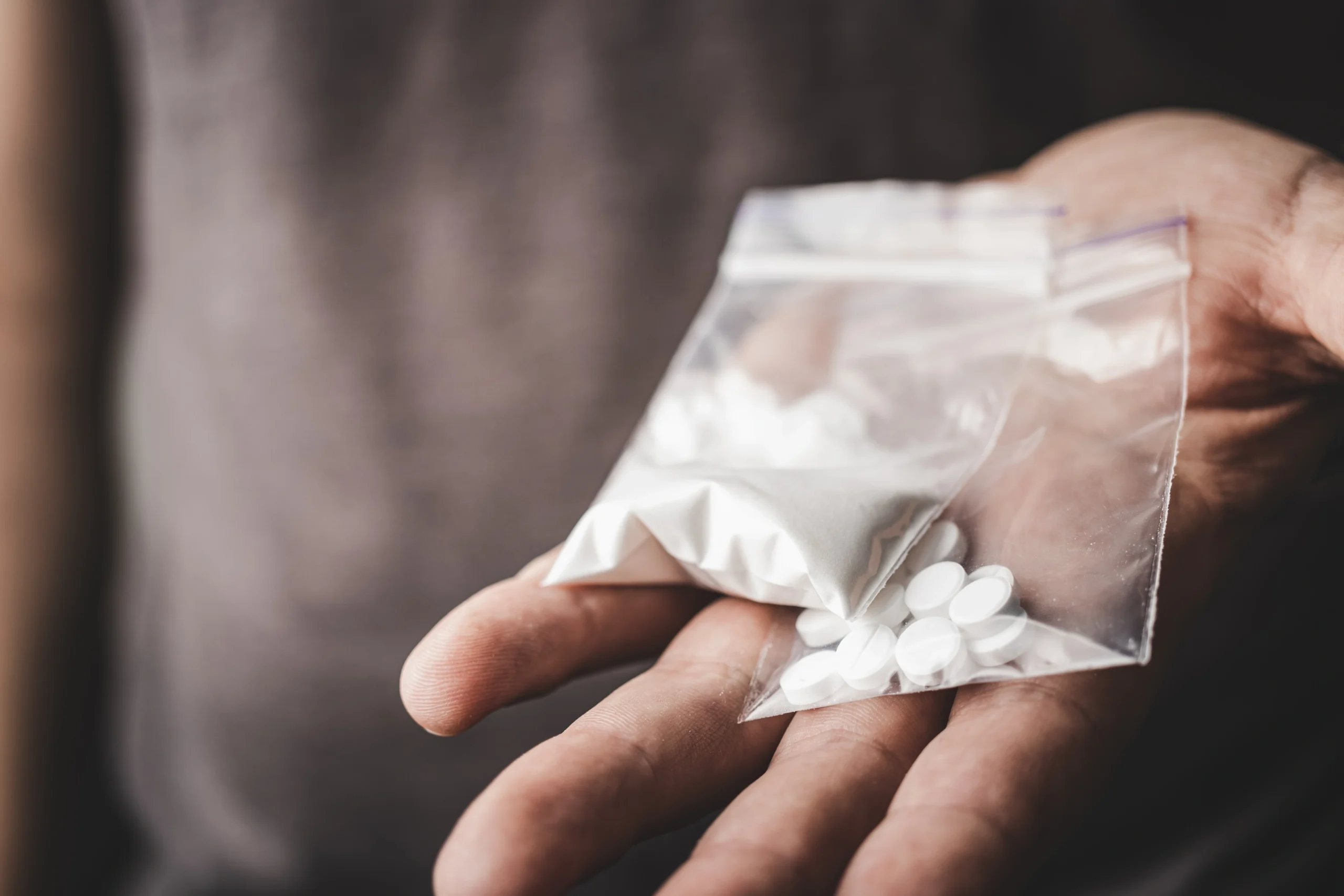 A man holds two small bags of drugs