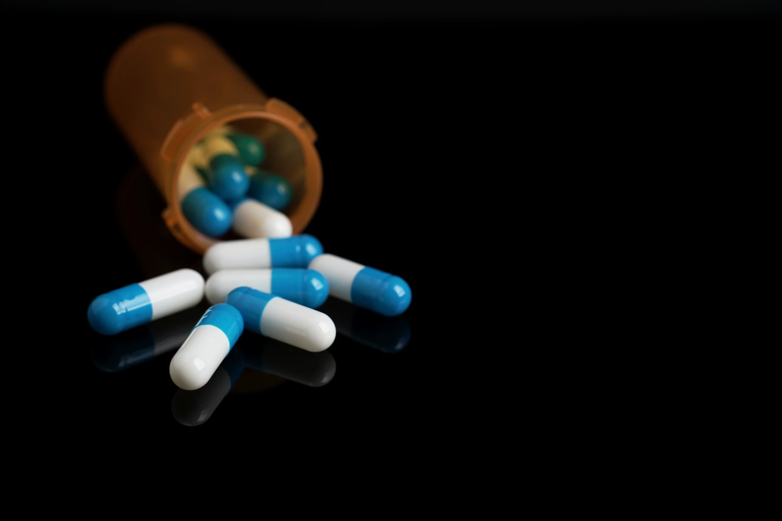 A prescription bottle is tipped over with pills spilling out