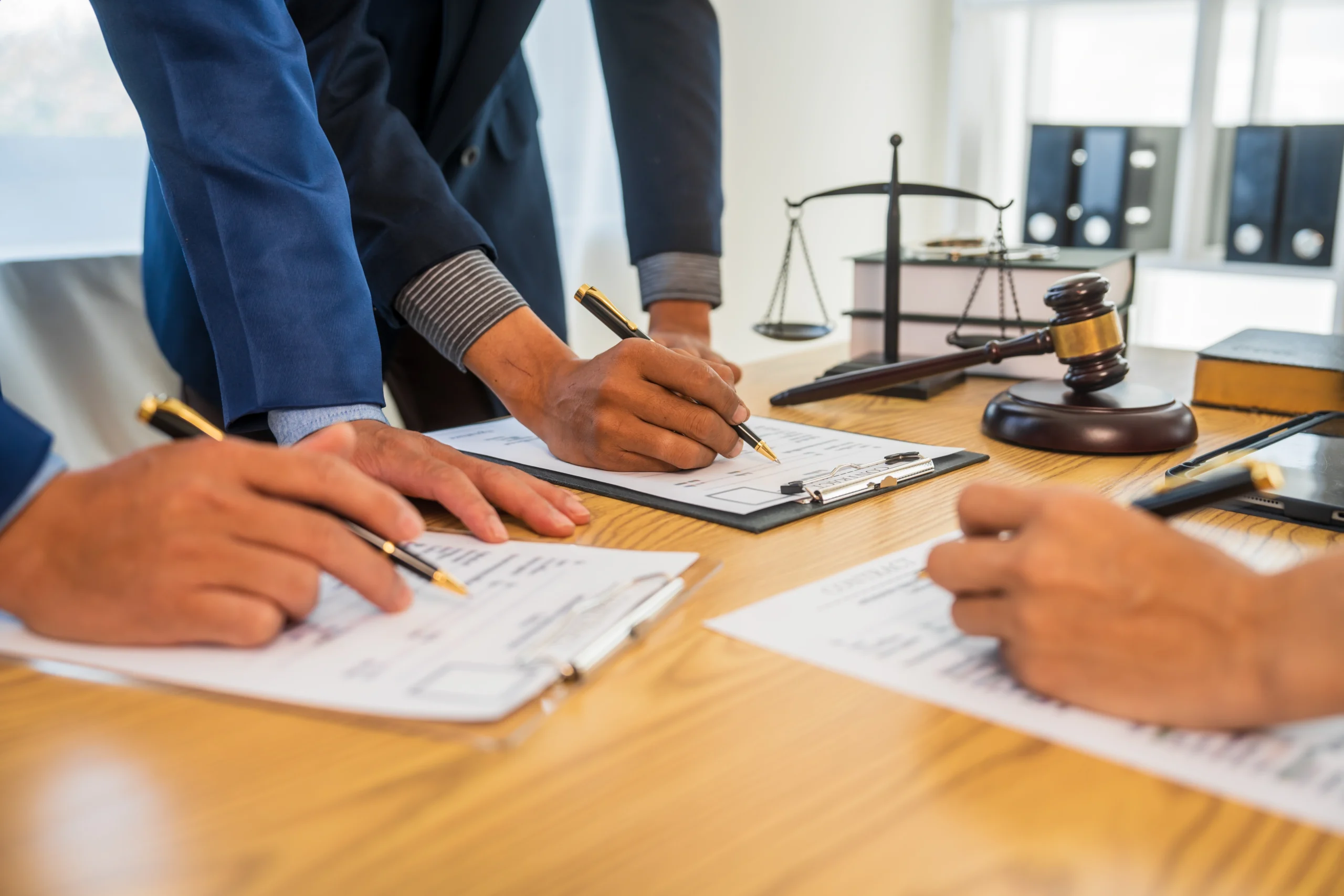 Three business people fill out forms at a law desk
