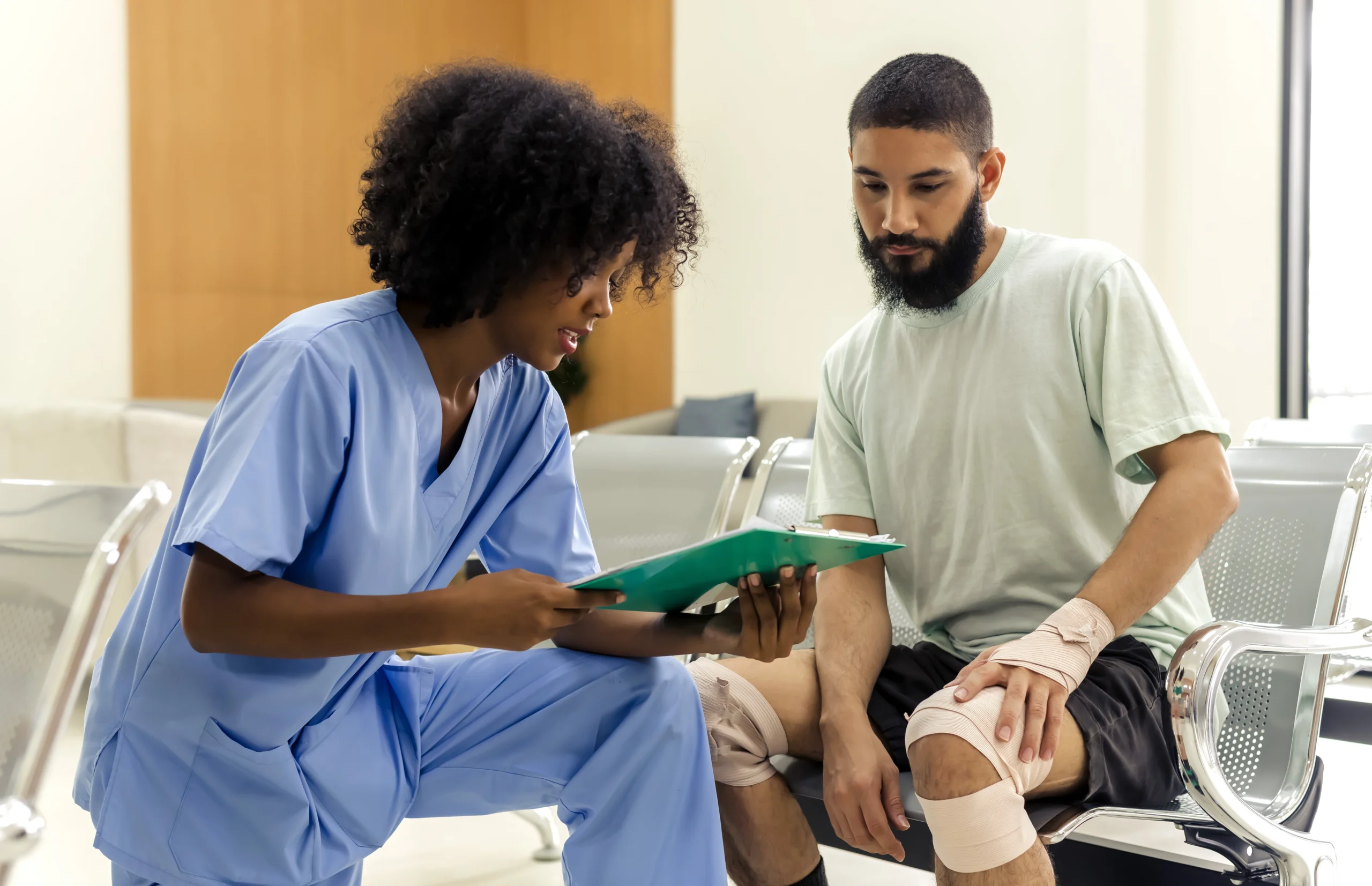 A health care professional reviews pages on a clipboard with a bandaged man