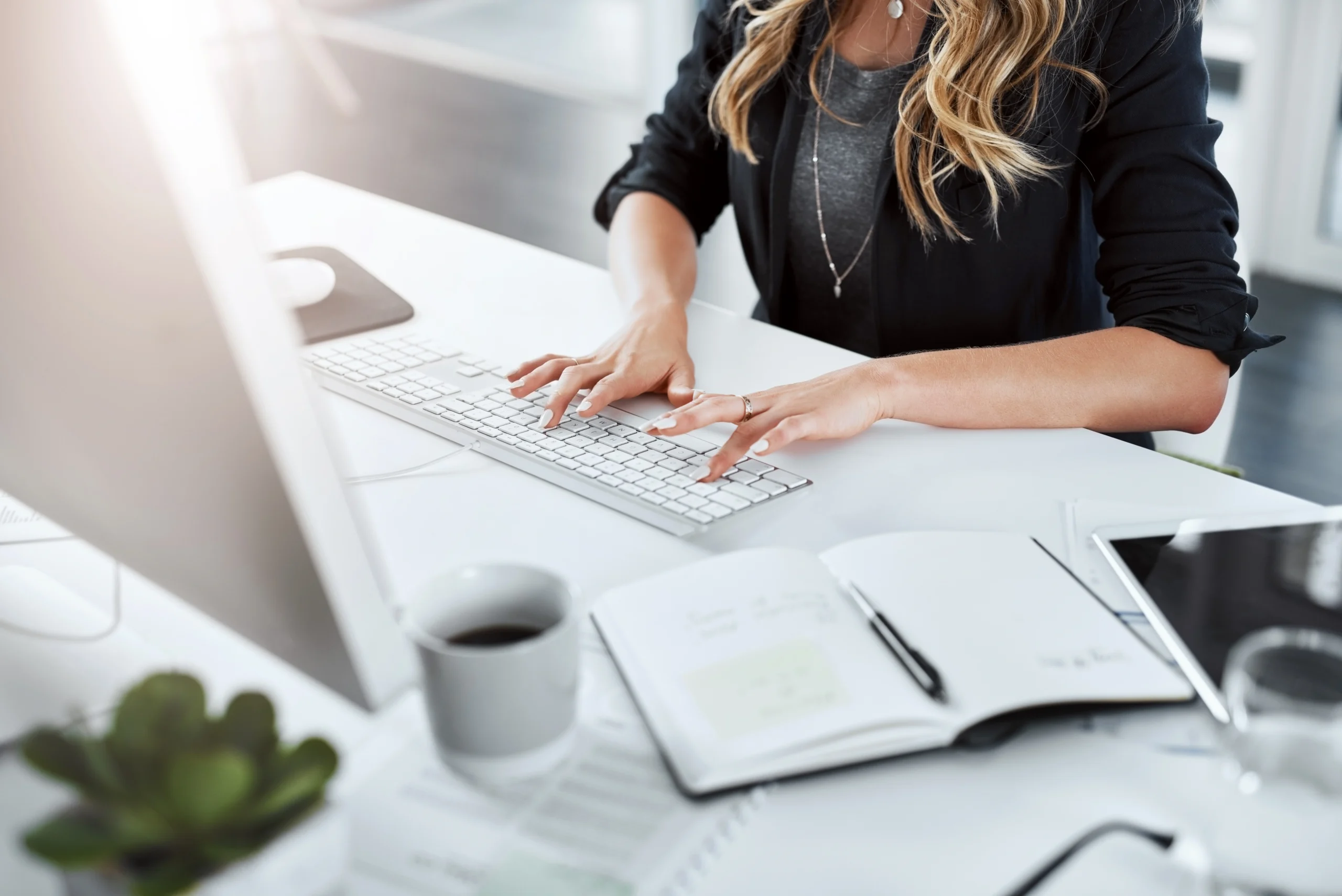 A business woman types on her computer at a desk