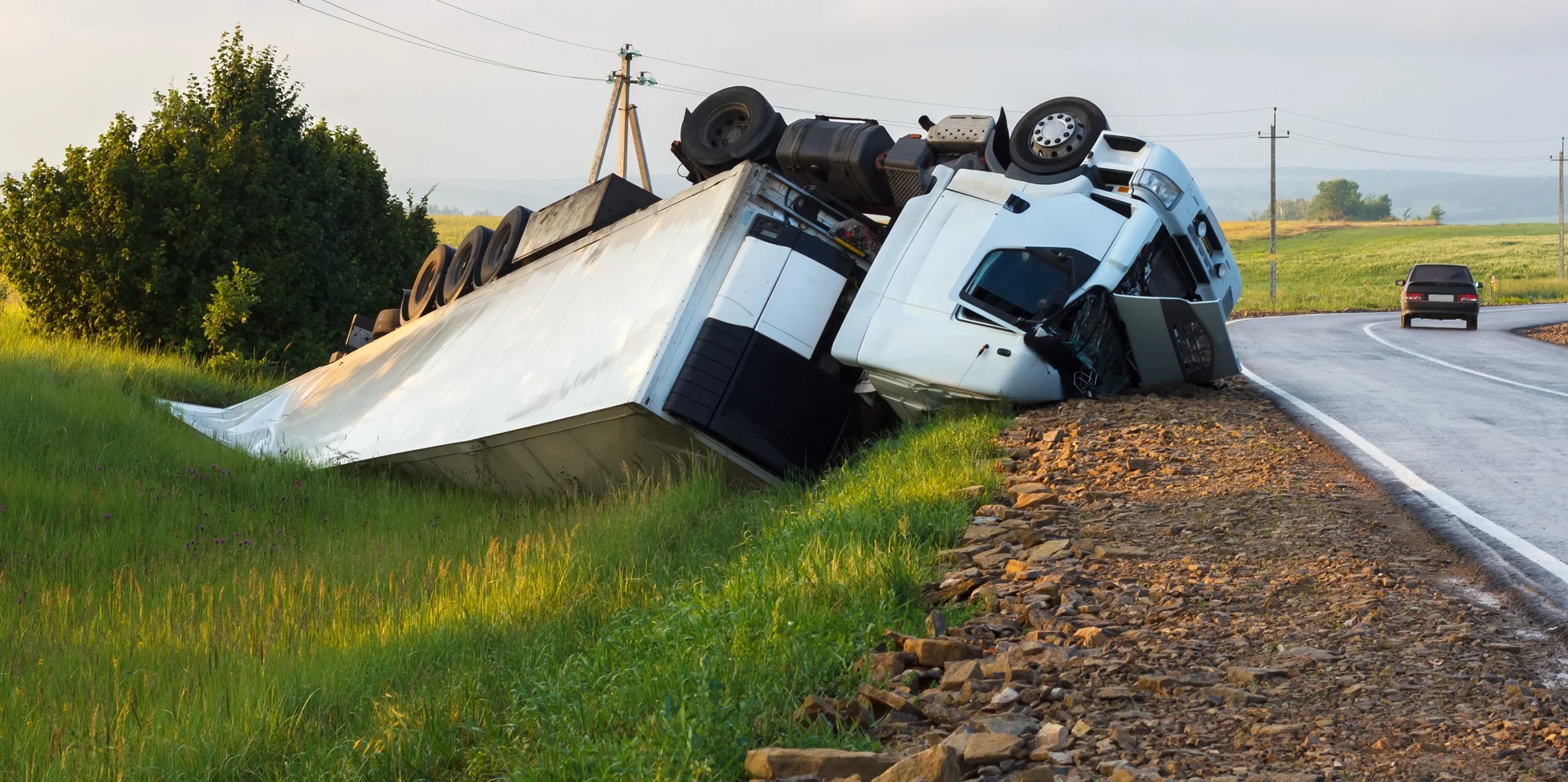 A semi truck is rolled over on the side of the road
